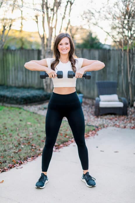 woman standing outside holding a pair of dumbbells